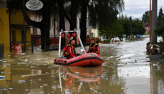 Volunteer firefighters ride their dinghy across a street flooded by the river Savio in the Ponte Vecchio district of Cesena, central eastern Italy, on May 17, 2023. —AFP