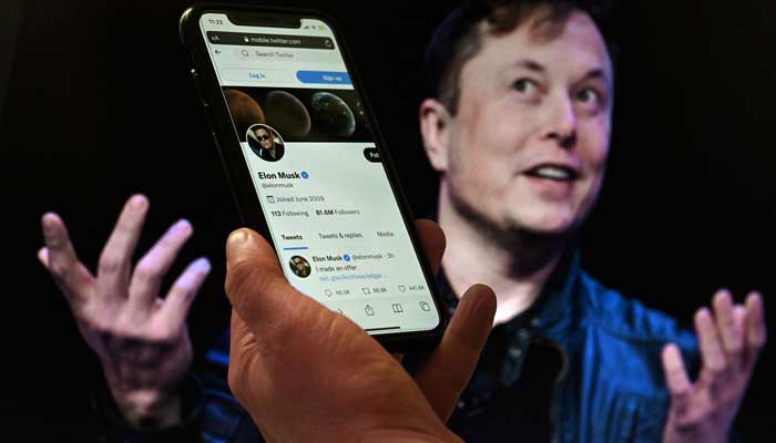 In this photo illustration, a phone screen displays the Twitter account of Elon Musk with a photo of him shown in the background on April 14, 2022 in Washington, DC. — AFP