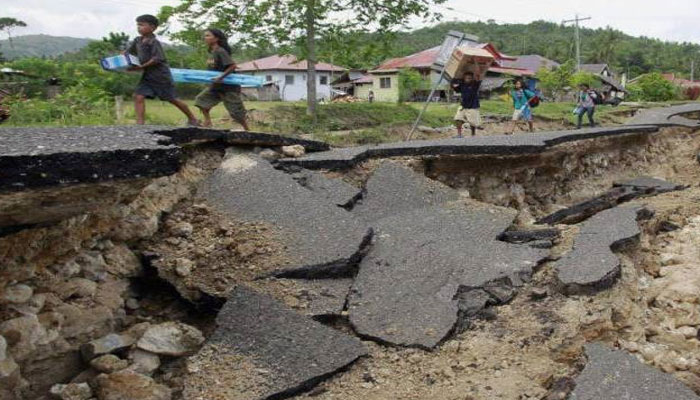 Yerel halk, depremde yıkılan bir yolun yanından geçiyor.  — AFP/Dosya