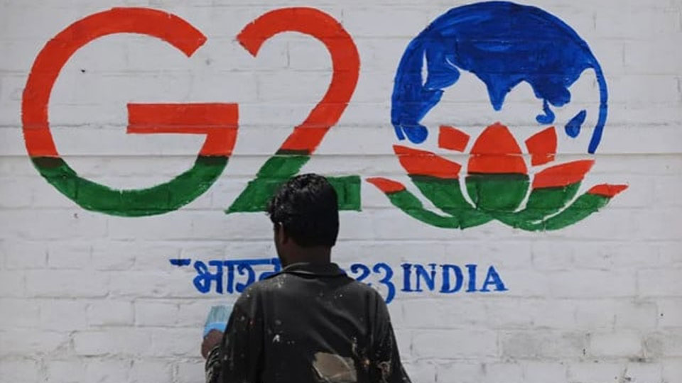 A man paints a wall with the G20 logo in Srinagar. — AFP