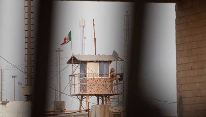 İranlı bir sınır muhafızı, 31 Ağustos 2022'de Irak'ın güneyindeki Basra kenti yakınlarındaki Shalamjah (Shalamcheh) geçişini Irak sınırının İran tarafındaki bir gözlem noktasından izliyor. — AFP