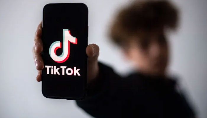 The picture shows a boy holding a smartphone with the TikTok logo displayed on the screen. — AFP/File