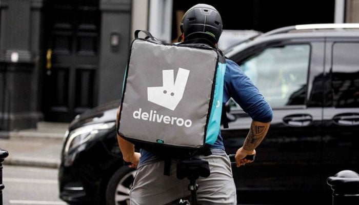 Questa immagine mostra un ragazzo delle consegne che si reca a consegnare cibo per l'app Deliveroo con sede nel Regno Unito.  — AFP/File