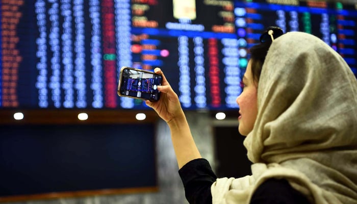 A woman takes a picture of share prices during a trading session at the Pakistan Stock Exchange (PSX) on December 21, 2022. — PPI