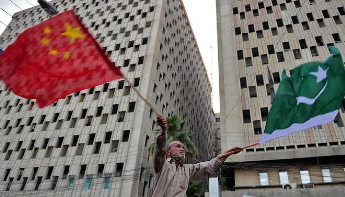 A Pakistani man waves Pakistani and Chinese national flags on a street of Karachi. — AFP/File