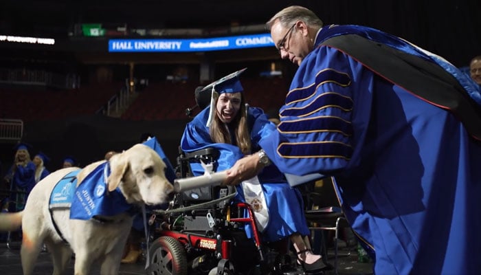 Seton Halls Joseph E. Nyre presents an honorary diploma to a students service dog named Justin during a graduation ceremony at the varsity, in this still taken from a video. — Twitter/@SetonHall