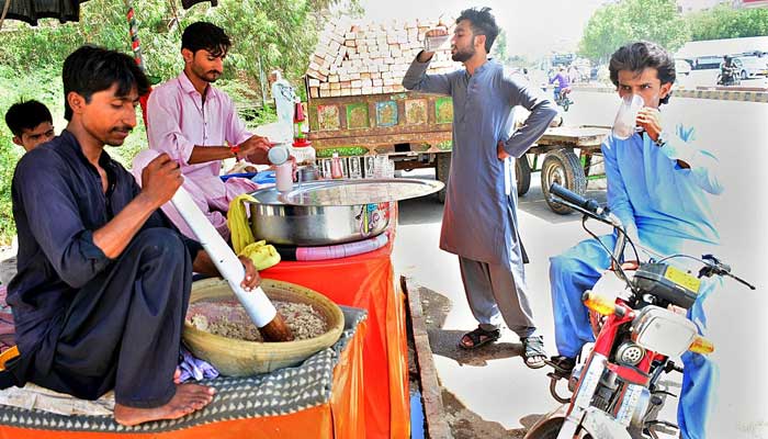 People drink traditional drink thadal from a vendor during hot weather in Hyderabad on May May 23, 2023. — APP