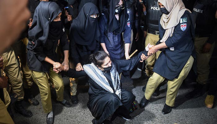 Policewomen detain a PTI party activist and supporter of former prime minister Imran Khan during a protest against the arrest of their leader, in Karachi on May 10, 2023. — AFP