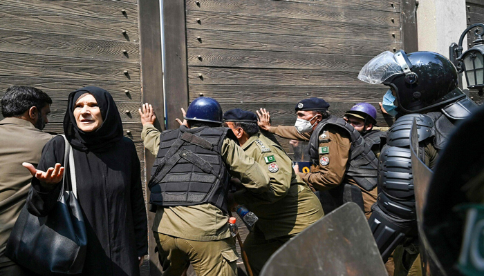Riot police push a main door to enter the residence of former prime minister Imran Khan, in Lahore on March 18, 2023, after he left for Islamabad to appear in a court. — AFP
