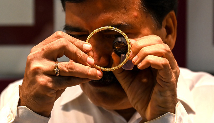 A shop manager examines a gold bracelet at a jewellery shop in Mumbai, India on Aug 11, 2021. — AFP