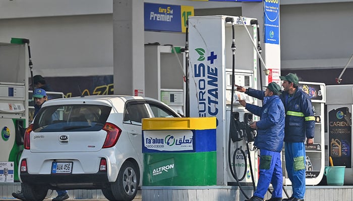 Employees at a fuel station in Islamabad attend to their customers, on February 16, 2022. — AFP