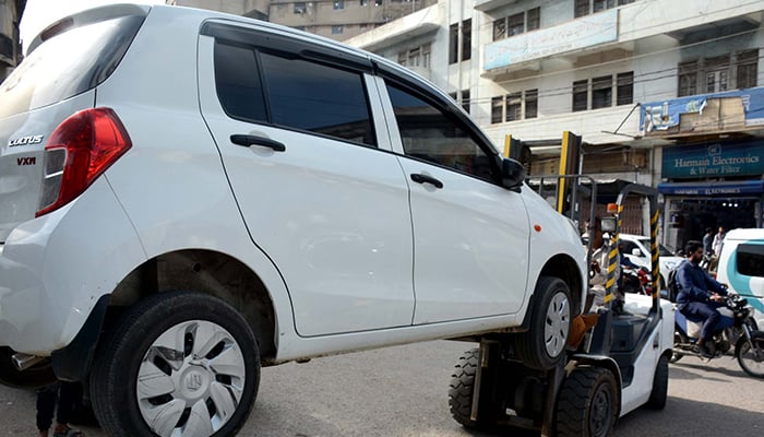 A traffic police car lifter lifts a vehicle that was parked in a no-parking area causing hurdles in the smooth flow of traffic at Saddars Regal Chowk in Karachi on April 3, 2023. — PPI