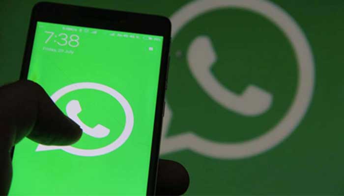A mans hand holding a smartphone with an illuminated screen showing WhatsApp logo. — AFP/File