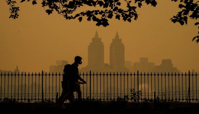 People walk in Central Park as smoke from wildfires in Canada causes hazy conditions in New York on June 7, 2023. — AFP