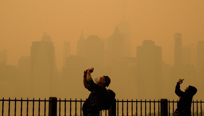 People take photos of the sun as smog causes hazy conditions in New York City, U.S., June 7, 2023. — AFP