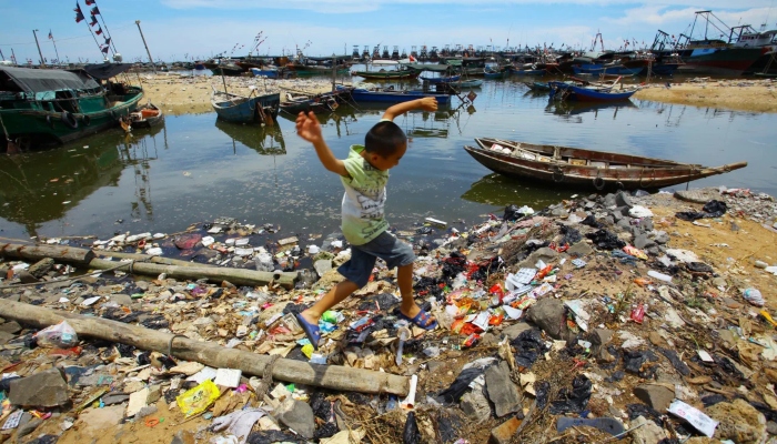 This representational picture shows a child playing by a littered lake. — AFP/File
