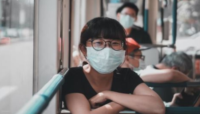 This representational picture shows an Asian woman smiling behind her face mask. — Unsplash/File