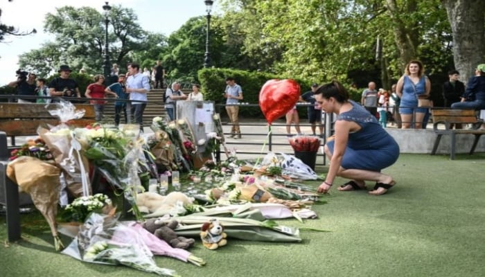 A woman places flowers near the site where children were stabbed on Thursday morning in a playground in the southeastern Alpine town of Annecy, France, taken on 9 June 2023. — AFP