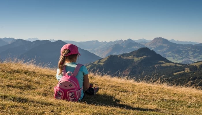 This representational picture shows a little girl sitting near the edge of a mountain overlooking other mountains. — Unsplash/File