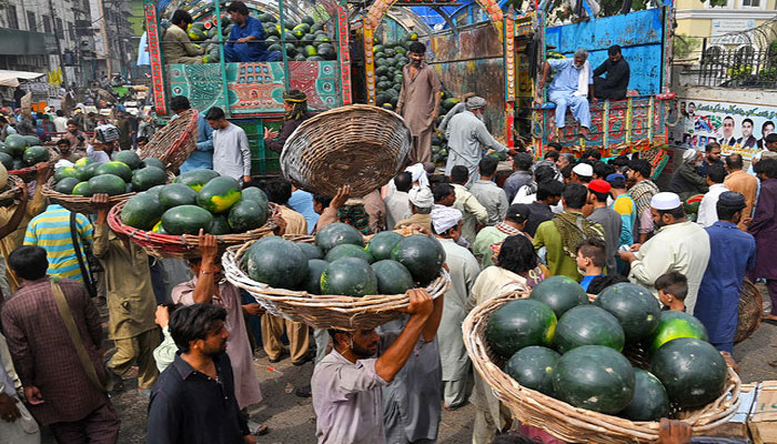 People trade watermelons at a fruit market in Lahore, Pakistan, on April 12, 2022. — AFP/File