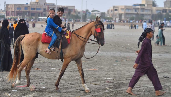 Children enjoy horse ridding during visiting at Seaview beach in Karachi. — INP