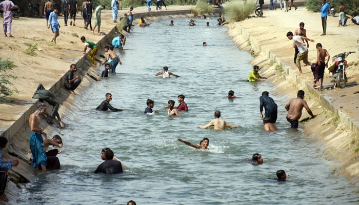 People bathing in a canal to cool themselves during extreme heat wave in Karachi on May 11, 2022. — Online