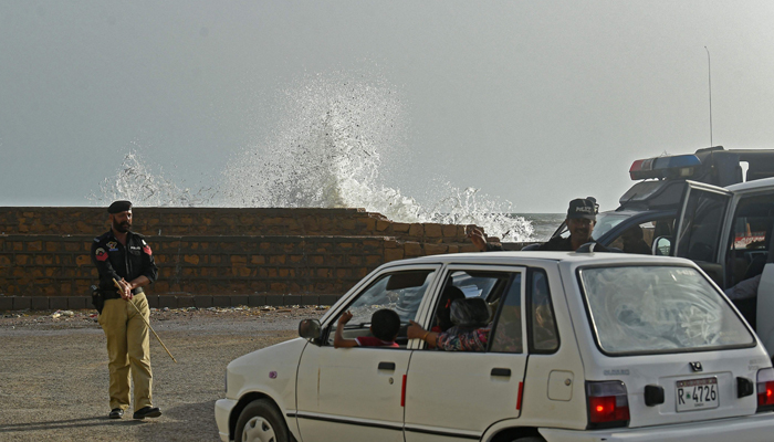 Policemen instruct people to vacate a beach before the due onset of cyclone Biparjoy in Karachi on June 12, 2023. — AFP