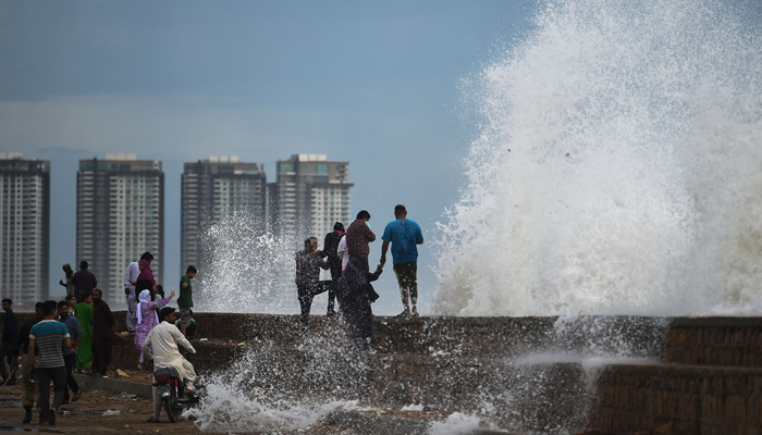 People enjoy high tides splashing on the sea front at a beach before the due onset of cyclone Biparjoy, in Karachi on June 13, 2023. — AFP