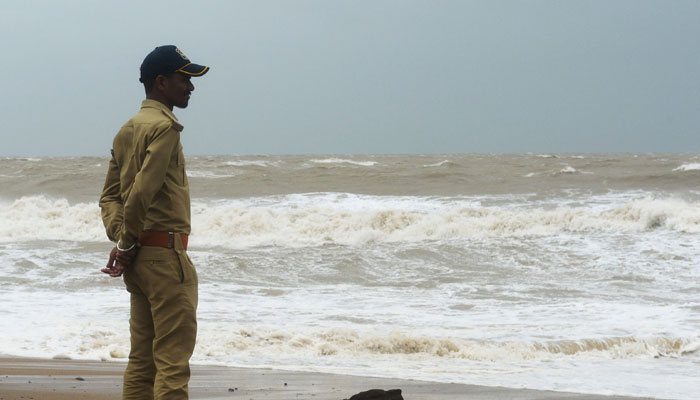 A policeman looks out as waves crash at Mandvi beach some 100 Km southeast of Jakhau Port on June 15, 2023, ahead of Cyclone Biparjoy landfall. — AFP
