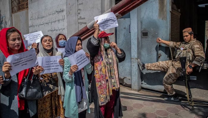 A Taliban fighter watches as Afghan women hold placards during a demonstration demanding better rights for women in front of the former Ministry of Women Affairs in Kabul, Sept. 19, 2021. — AFP