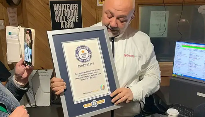 Radio host Mario Bekes holds his Guinness World Record Plaque in his studio. — Guinness World Records/File