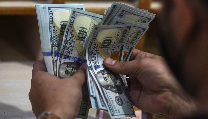 A currency exchange dealer counts $100 bills. — AFP/File