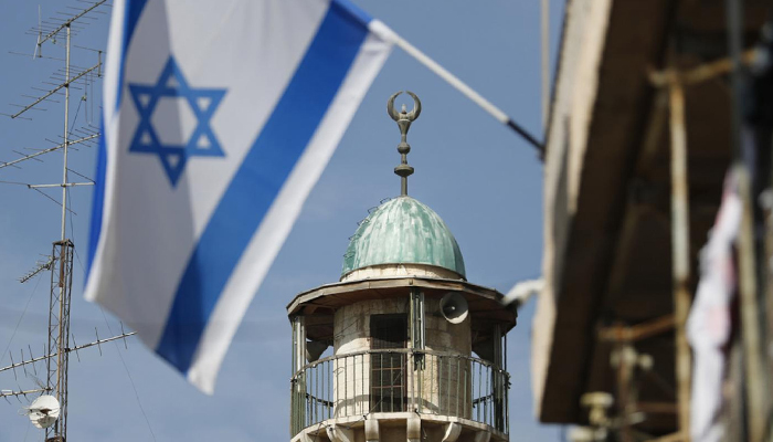 An Israeli flag waves in front of the minaret of a mosque in the Arab quarter of Jerusalems Old City. — AFP