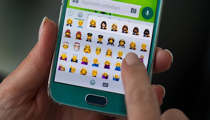An undated image of a person using WhatsApp with the emojis seen on the keyboard. — AFP/File