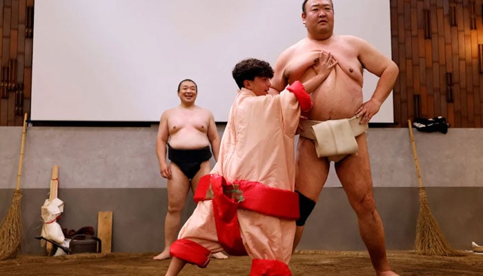 A tourist wearing a sumo wrestler costume tries to spar against former sumo wrestler Towanoyama in the sumo ring at Yokozuna Tonkatsu Dosukoi Tanaka.— CNN