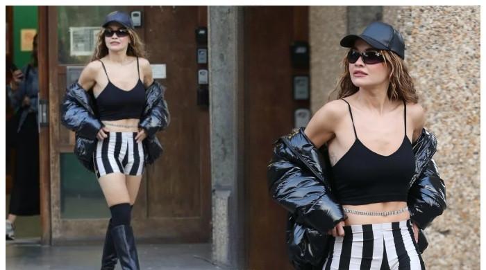 Rita Ora displays her toned figure in a black crop top and grey