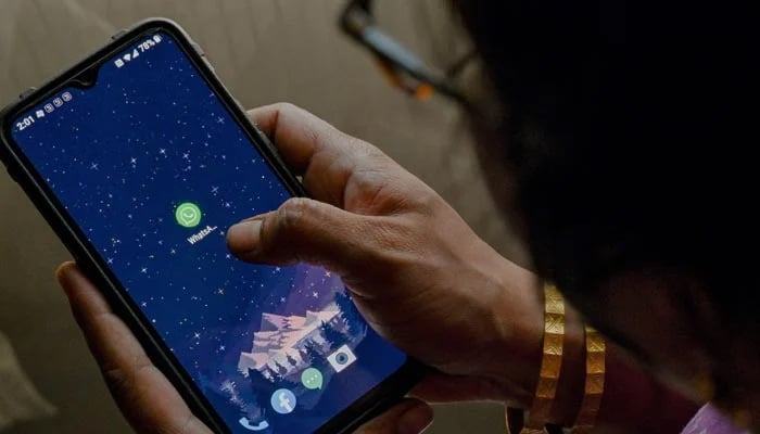 This photo illustration shows a woman checking the settings of the messaging application WhatsApp, in Bangalore on October 25, 2022. — AFP