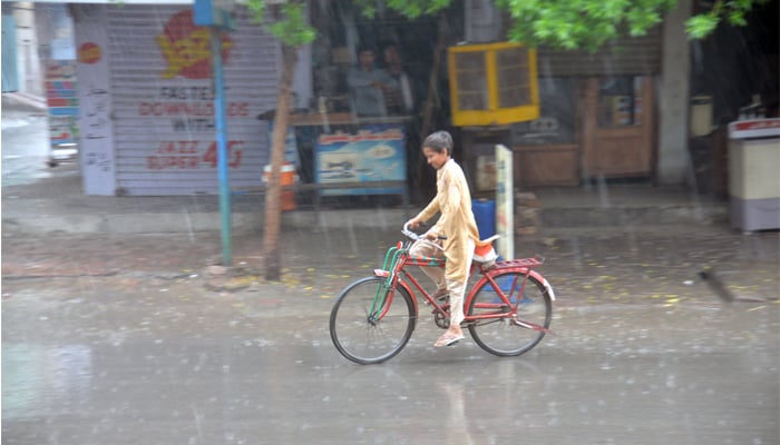 A cyclist is on his way during heavy rain fall in Faislabad on July 13, 2023. — Online