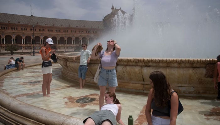 This picture eople cool off with a fountains water during a heat wave in Seville, Spain on July 12. — AFP/File