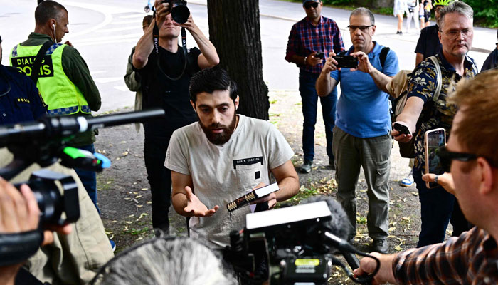 Ahmad A. (C) outside the Israeli embassy in Stockholm, Sweden, surrounded by journalists on July 15, 2023, after he chose not to burn the books but to hold a manifestation holding a Quran in his hand. — AFP