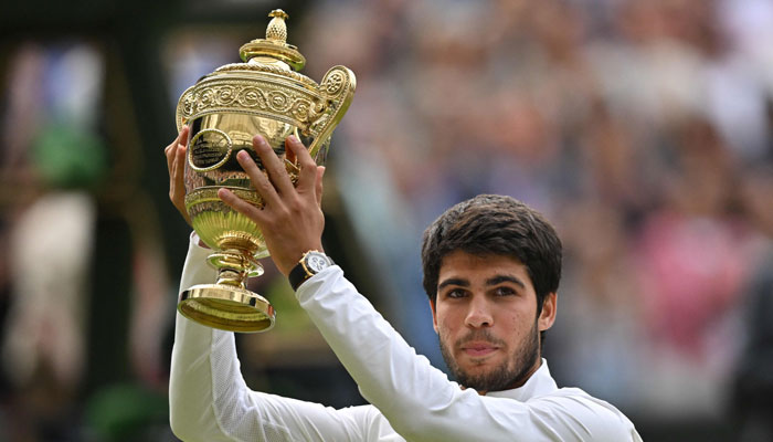 Spains Carlos Alcaraz raises his trophy after beating Serbias Novak Djokovic during their mens singles final tennis match on the last day of the 2023 Wimbledon Championships at The All England Tennis Club in Wimbledon, southwest London, on July 16, 2023. — AFP