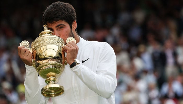 Spains Carlos Alcaraz kisses the winners trophy after beating Serbias Novak Djokovic during their mens singles final tennis match on the last day of the 2023 Wimbledon Championships at The All England Tennis Club in Wimbledon, southwest London, on July 16, 2023. — AFP