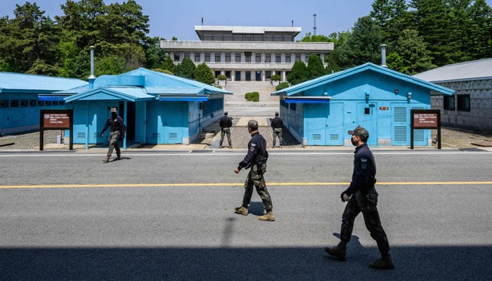 In this photo taken on May 9, 2023, South Korean soldiers walk at the truce village of Panmunjom in the Joint Security Area (JSA) of the Demilitarized Zone (DMZ) separating North and South Korea, with a view of North Koreas Panmon Hall (back C). — AFP