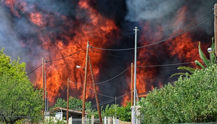 An image of a wildfire raging by houses in the settlement of Irini, some 80 kilometres east of Athens – AFP/Files