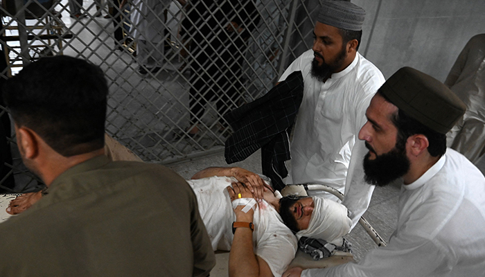 People shift an injured victim into a hospital in Peshawar on July 30, 2023. — AFP