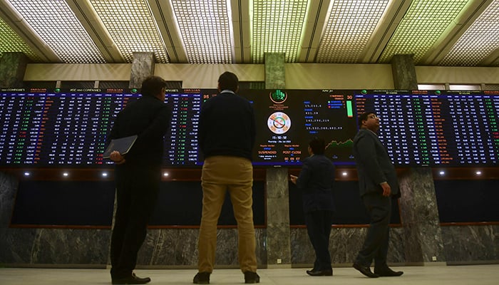 Brokers monitor an index board showing latest share prices at the Pakistan Stock Exchange in Karachi on January 26, 2023. — AFP