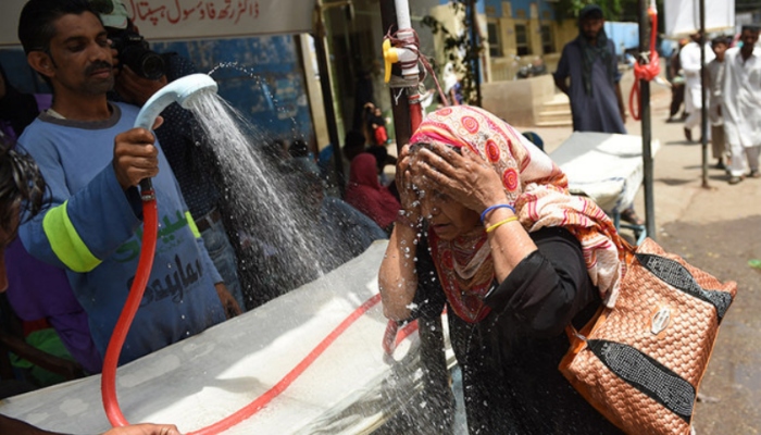 A volunteer douses a woman with water during the heatwave in Karachi. — AFP/File