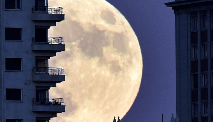 Moon rises in background of a building in Madrid aon November 13, 2016, on the eve of a supermoon. — AFP