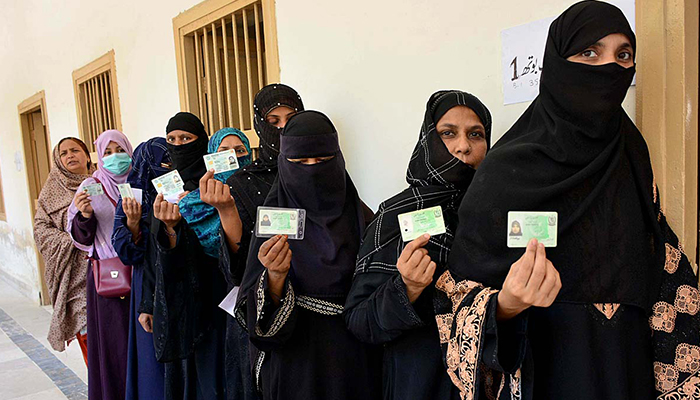 Women showing their National Identity Cards while standing in a queue at a polling station to cast their votes during an election in Hyderabad, on May 7, 2023. — APP