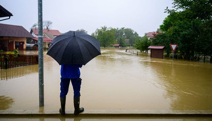This photograph taken on August 5, 2023 shows a man looking at the houses flooded by the rising water of the river Krka, in the village of Velike Malence, south-east Slovenia. — AFP